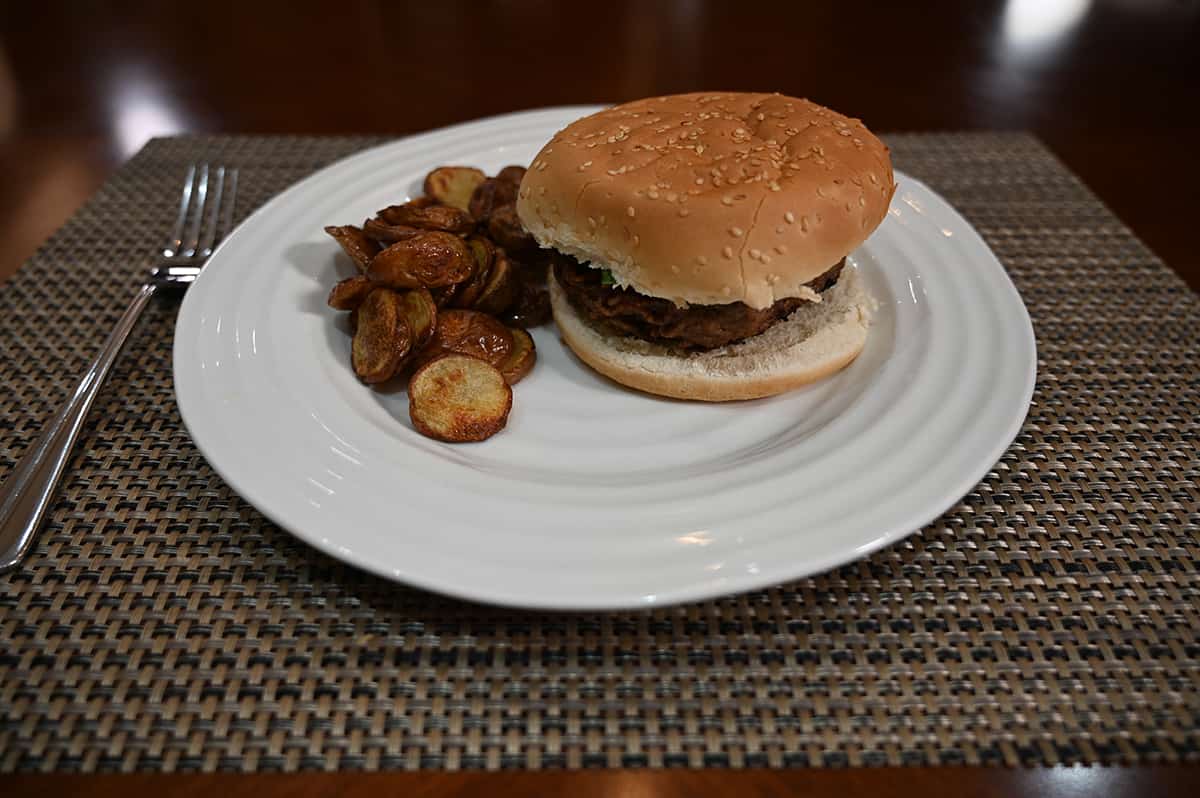 Image of a hamburger beside oven baked mini potatoes on a white plate.