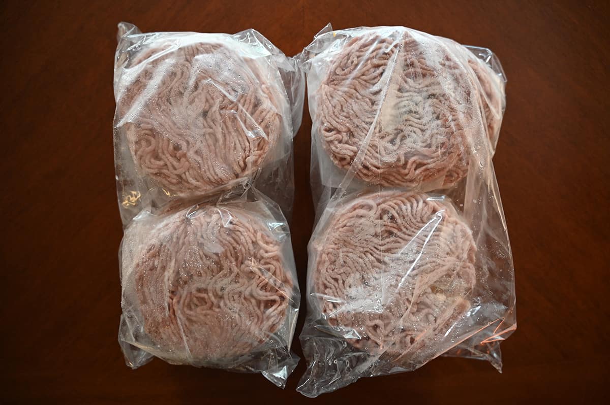 Image of two plastic bags with raw burgers sealed in them sitting on a table.