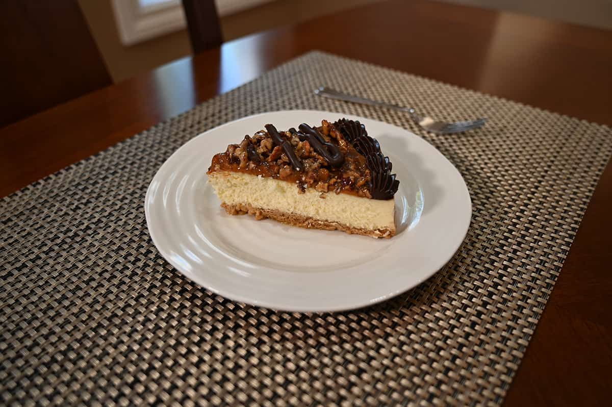 Sideview top down image of one slice of cheesecake on a white plate with a fork beside it.