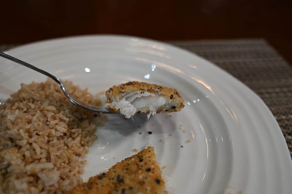 Closeup image of a bite of cod on a fork so you can see how the cod looks, it appears flaky and moist.