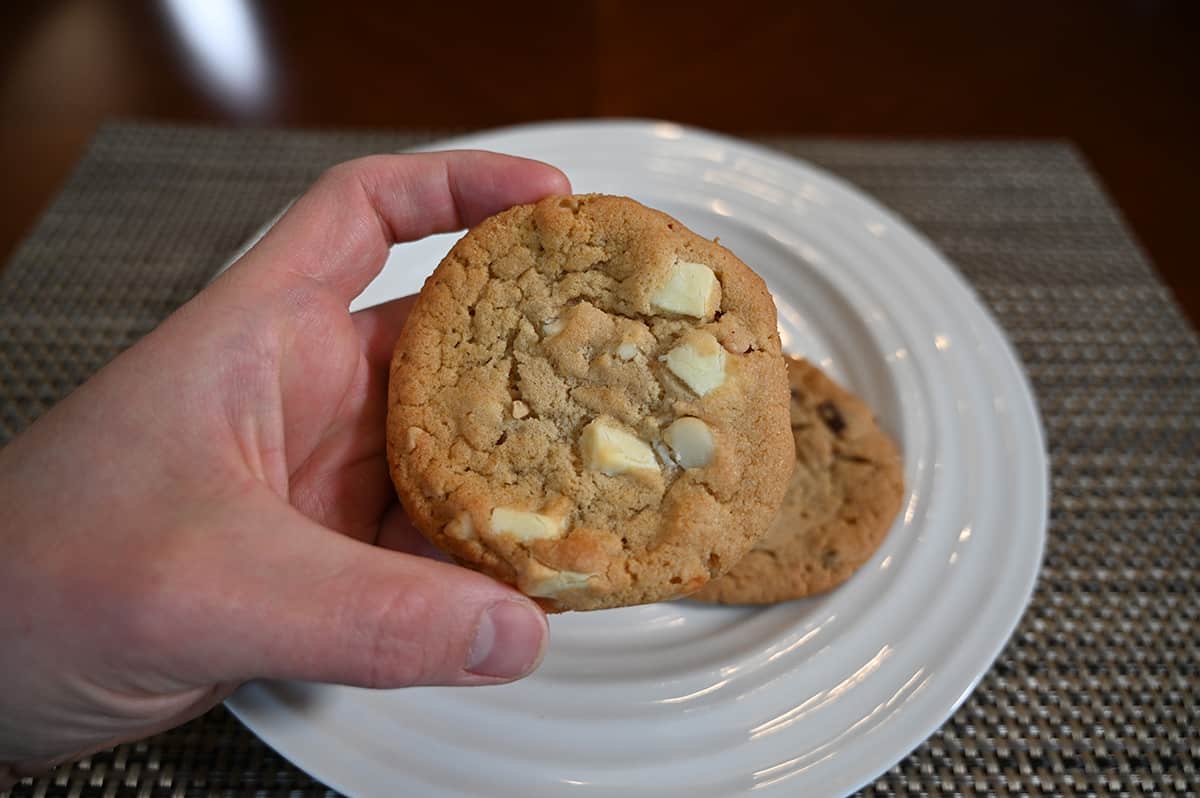 Closeup image of a hand holding a double nut cookie close to the camera.
