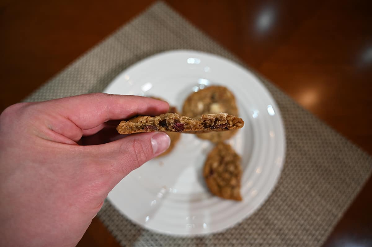 Closeup side image of a hand holding one cookie close to the camera with a few bites taken out so you can see what the center of the cookie looks like.