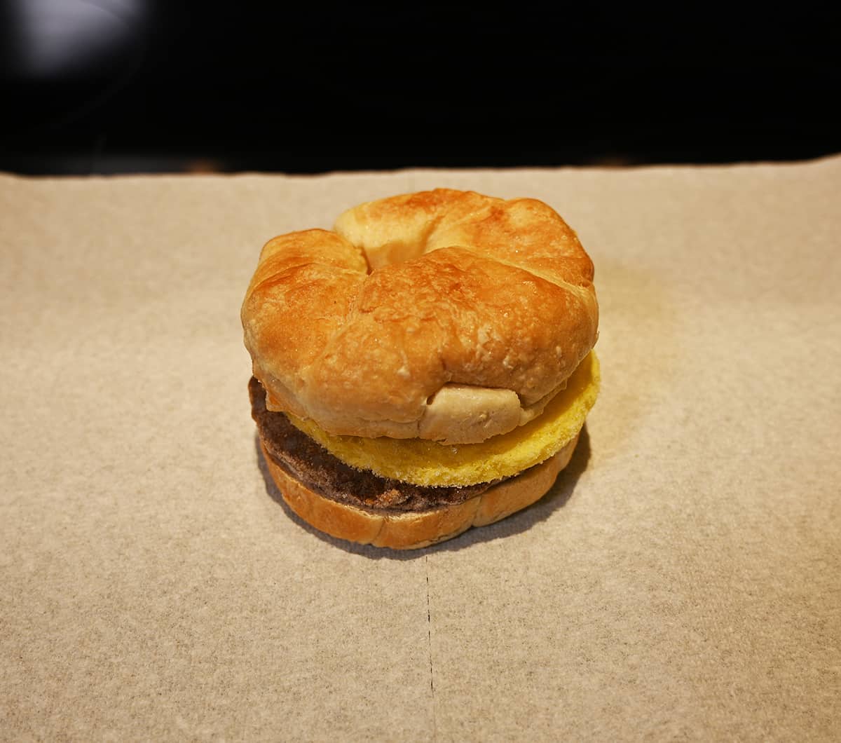 Image of a croissant sandwich sitting on a piece of paper towel after being heated in the microwave.