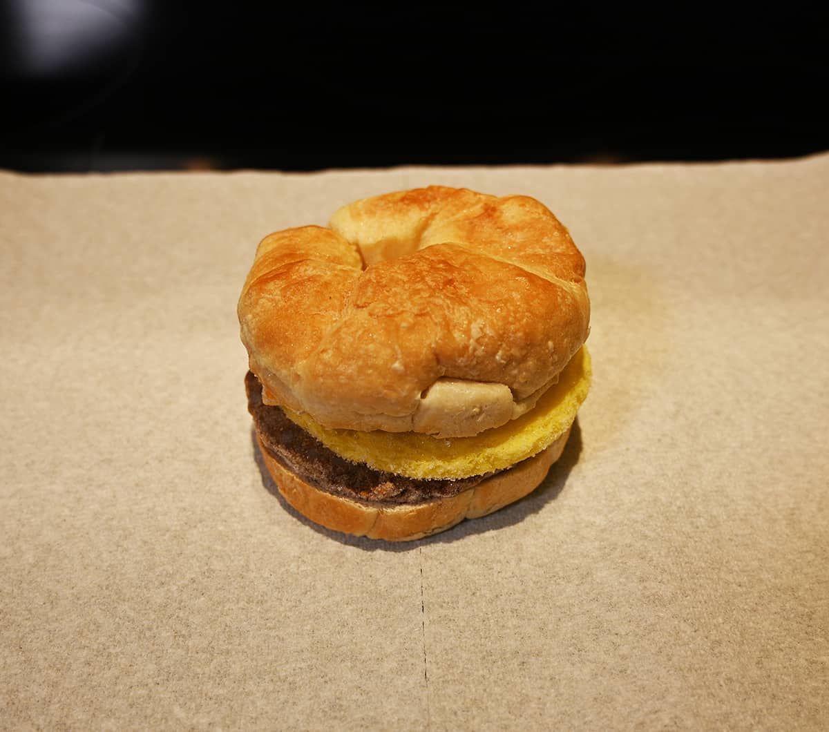 Image of a croissant sandwich sitting on a piece of paper towel after being heated in the microwave.