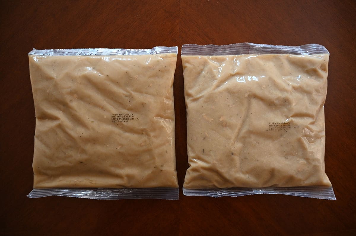 Top down image of two large plastic pouches of gravy sitting on a table unopened.