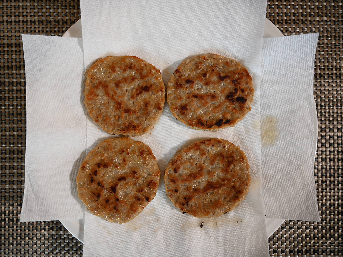 Top down image of four sausage rounds cooked and sitting on a paper towel.