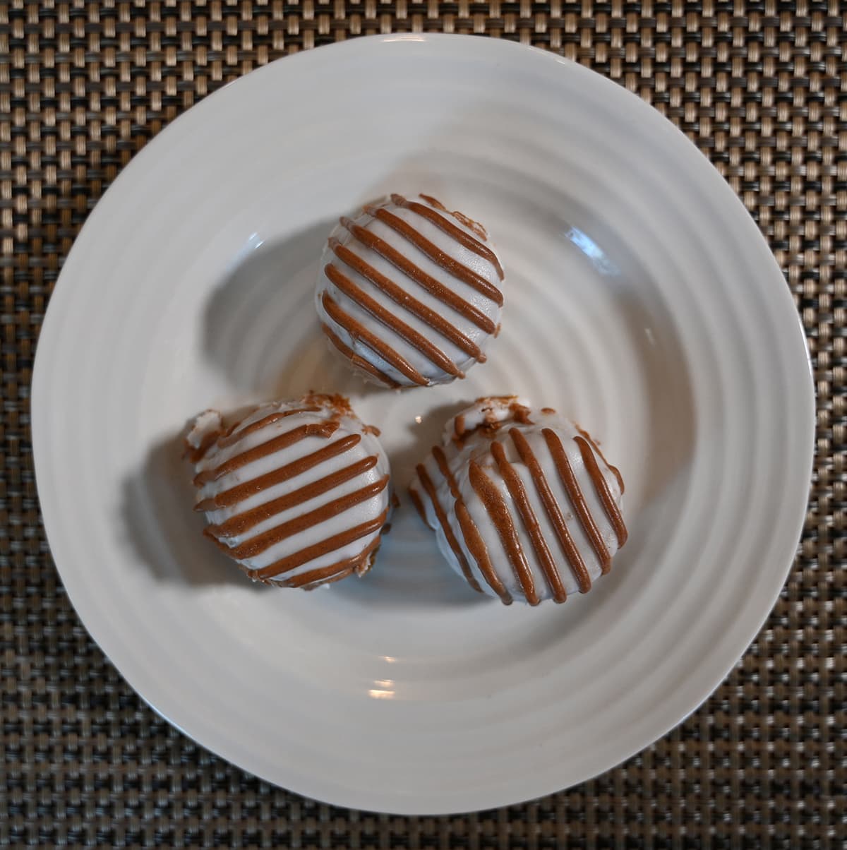 Top down image of three pumpkin spice bites served on a white plate.