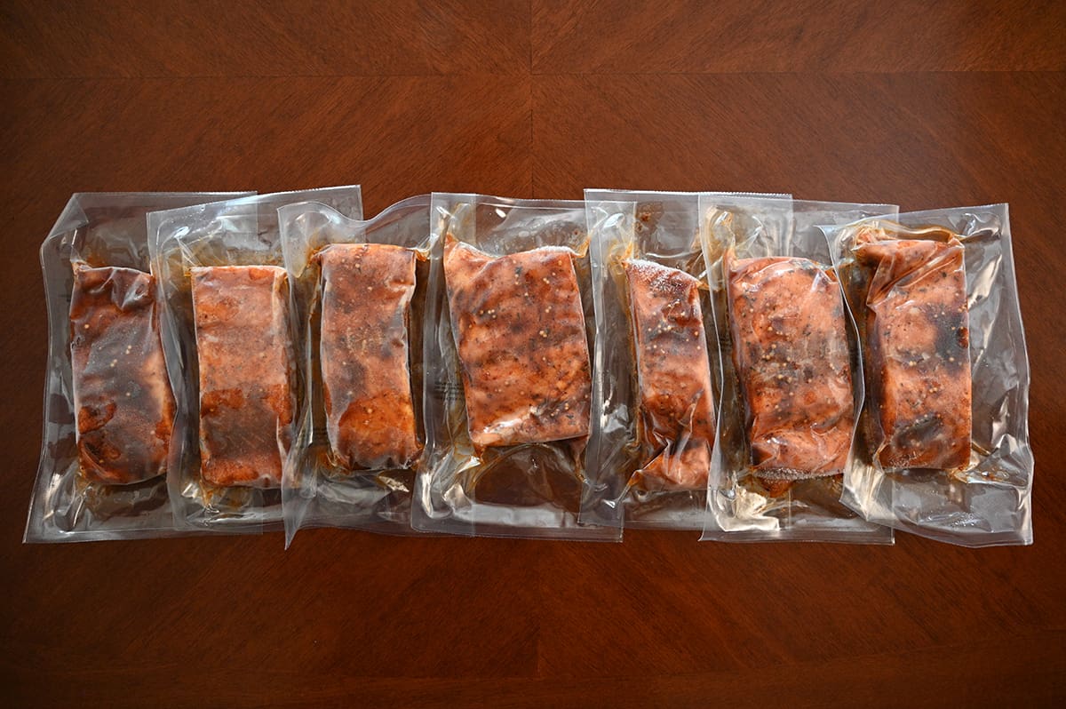 Top down image of seven individually vaccum sealed salmon fillets on a table.