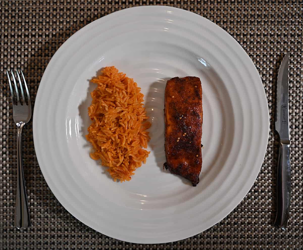 Top down image of a cooked salmon fillet beside a chili lime rice. Served on a plate.