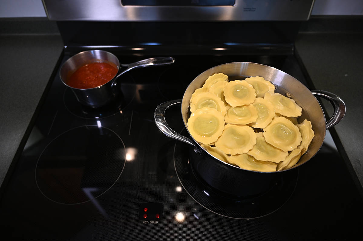 Top down image of a pot of pasta boiling and pot of sauce cooking on a stovetop.
