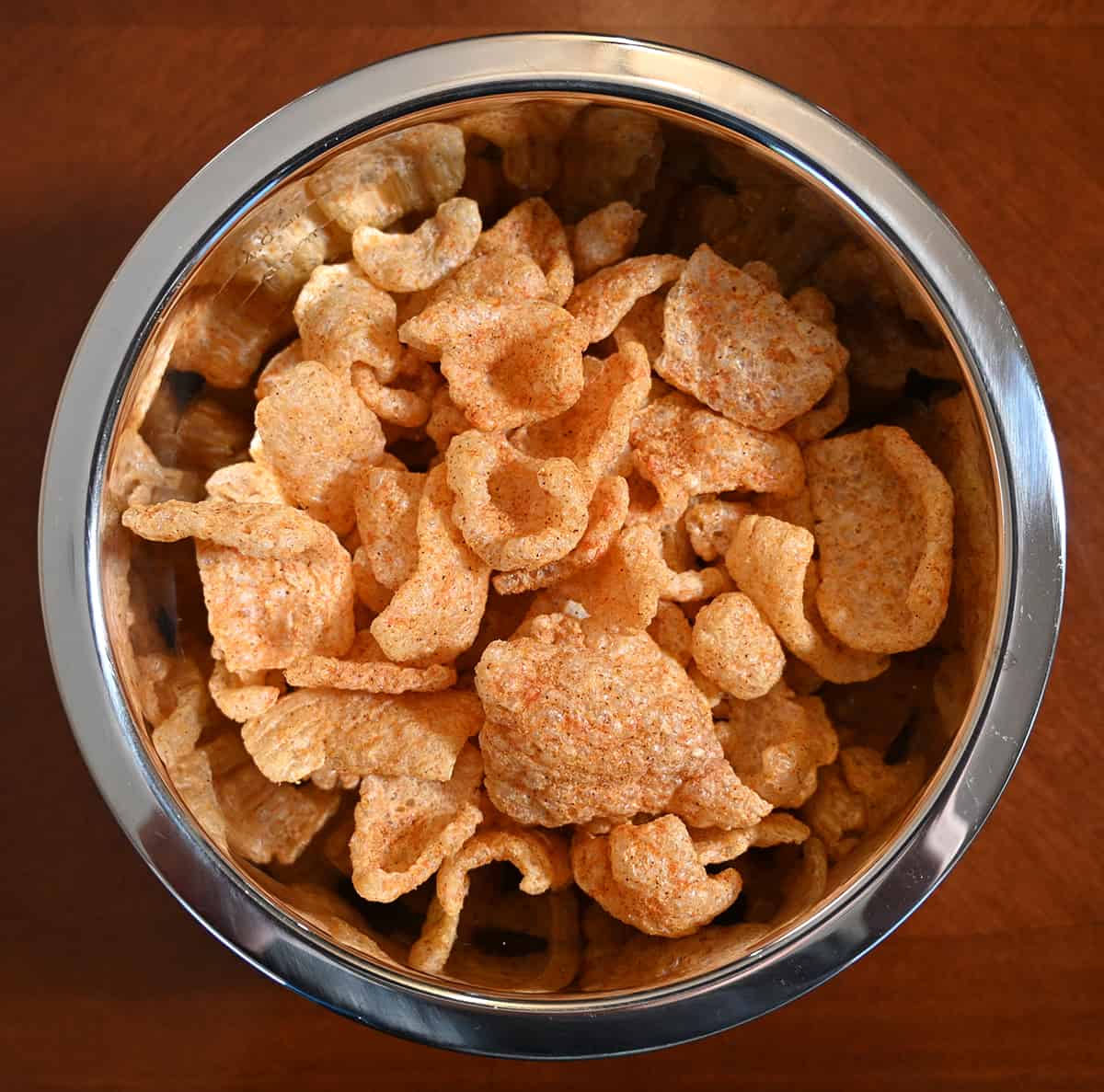 Top down image of a metal bowl full of pork rinds of all different shapes and sizes.