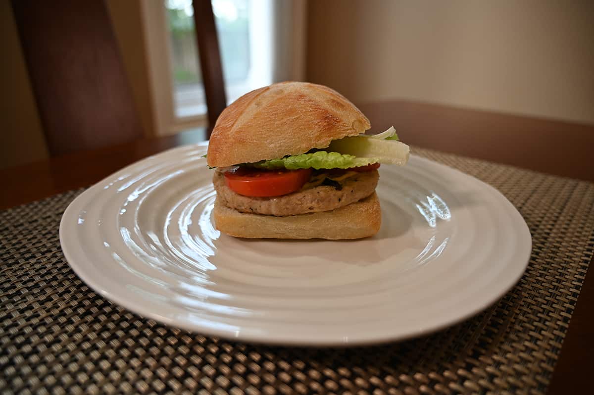 Image of a prepared chicken burger served on a white plate, there is lettuce and tomato in the burger.