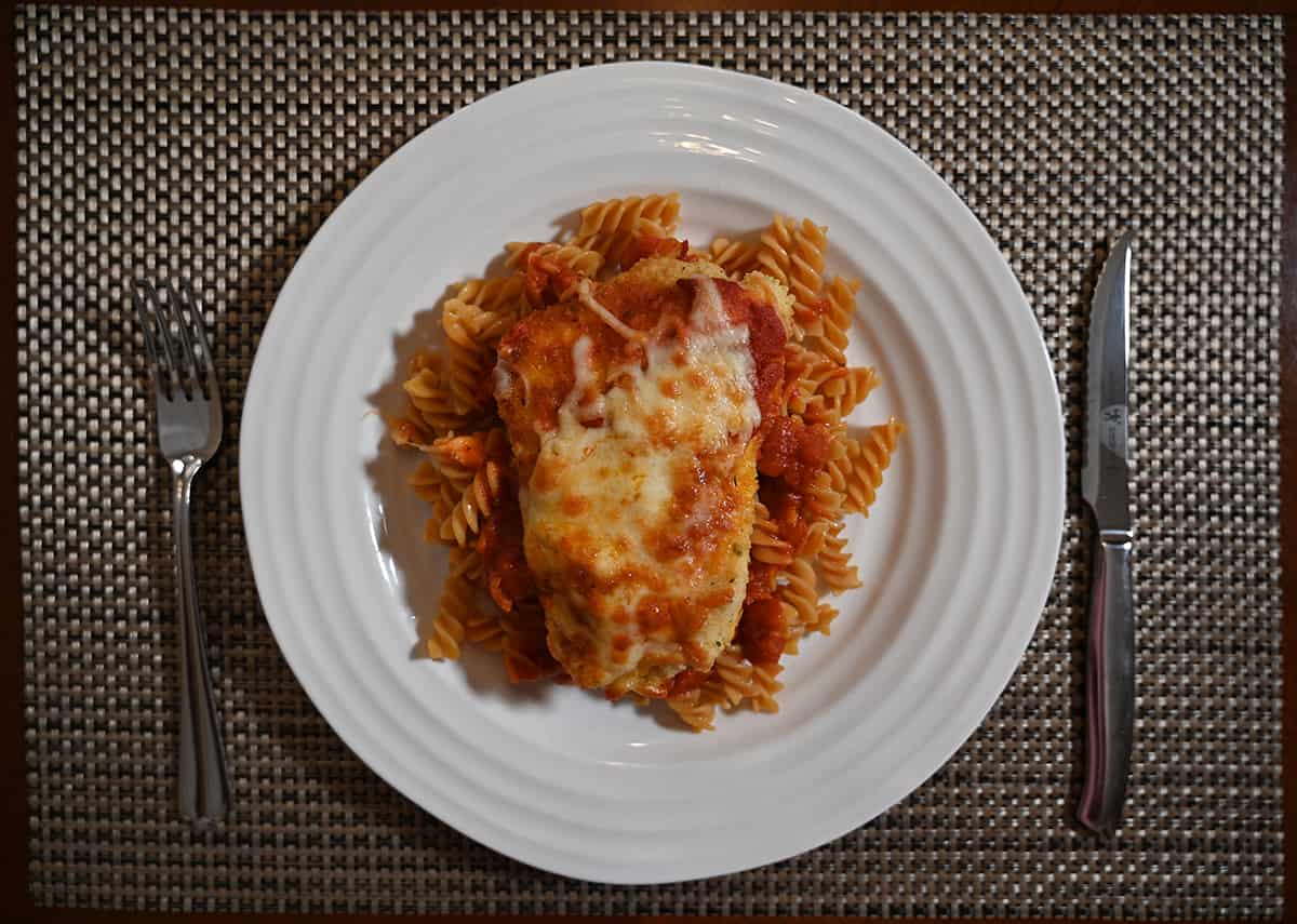 Top down image of the chickpea pasta served on a white plate alongside chicken parmesan.