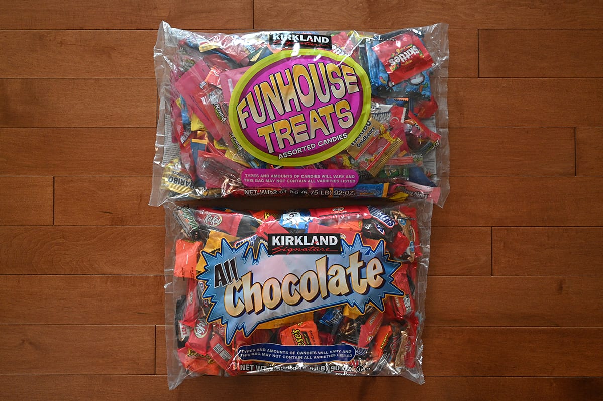 Top down image of two large bags of Costco Halloween Candy on a table unopened. One has chocolate bars and the other candy.