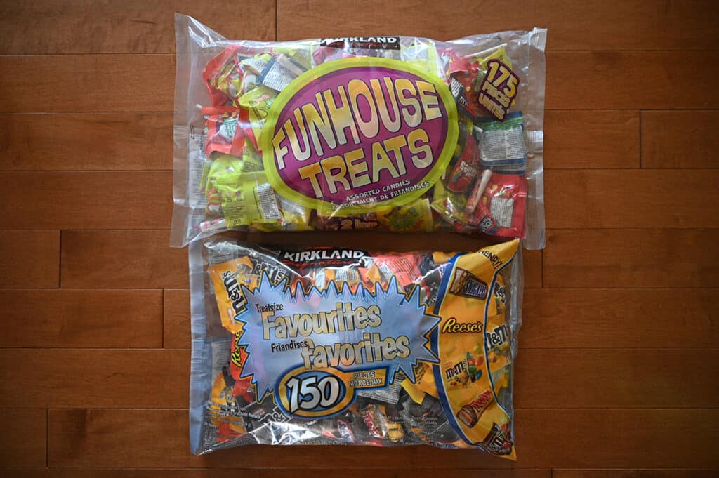 Top down image of two large bags of Costco Halloween Candy on a table unopened. One has chocolate bars and the other candy.