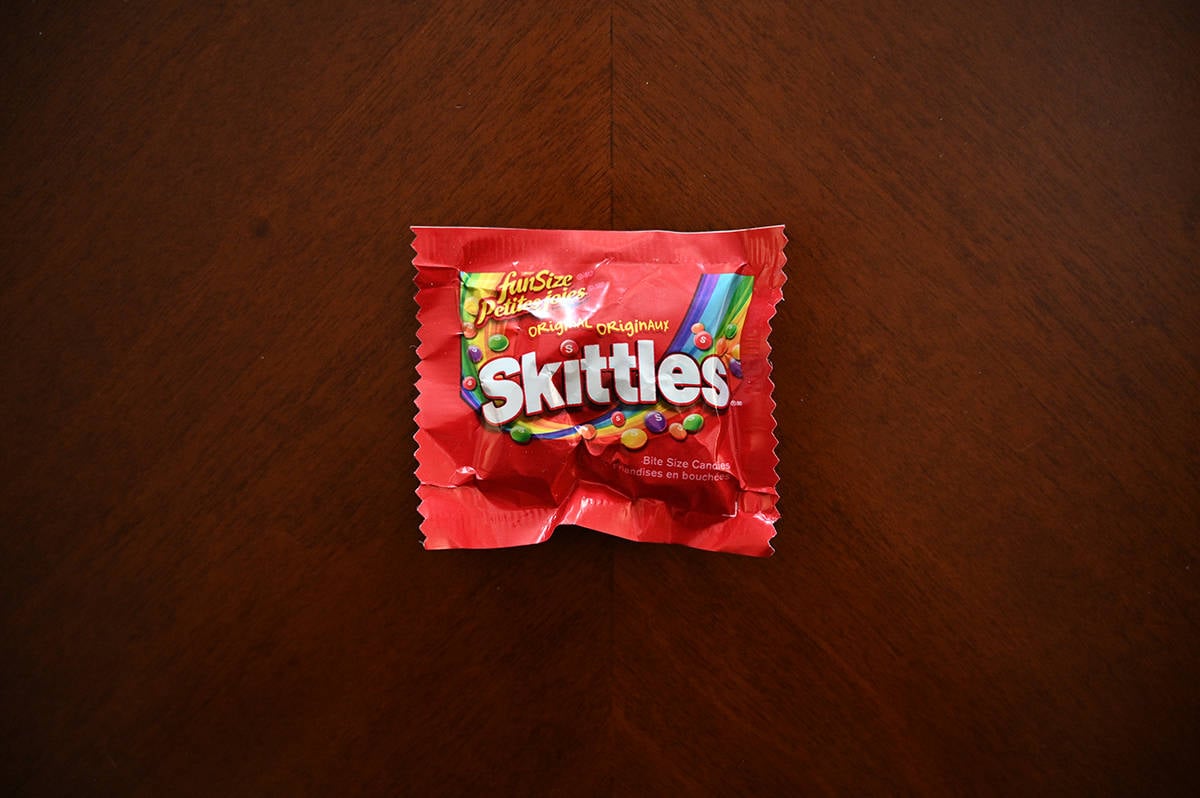 Top down image of an unopened bag of Skittles sitting on a table.