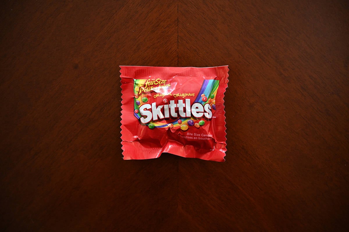Top down image of an unopened bag of Skittles sitting on a table.