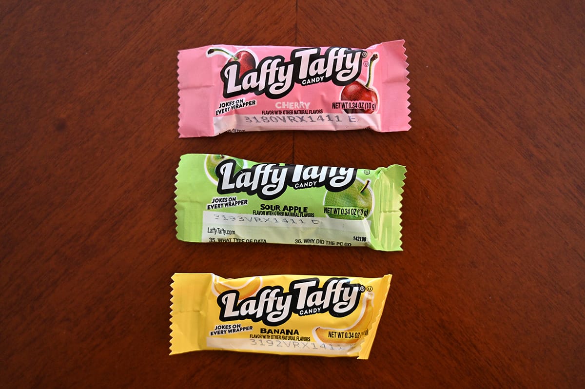 Top down image of three laffy taffy candies unopened sitting on a table. There are three kinds, apple, cherry and banana. 