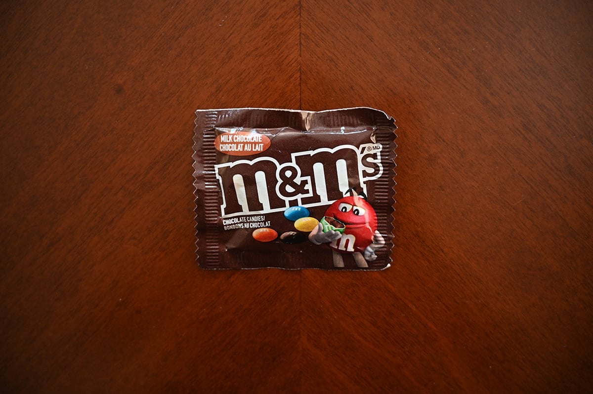 Top down image of a bag of milk chocolate M&M's sitting on a table unopened.