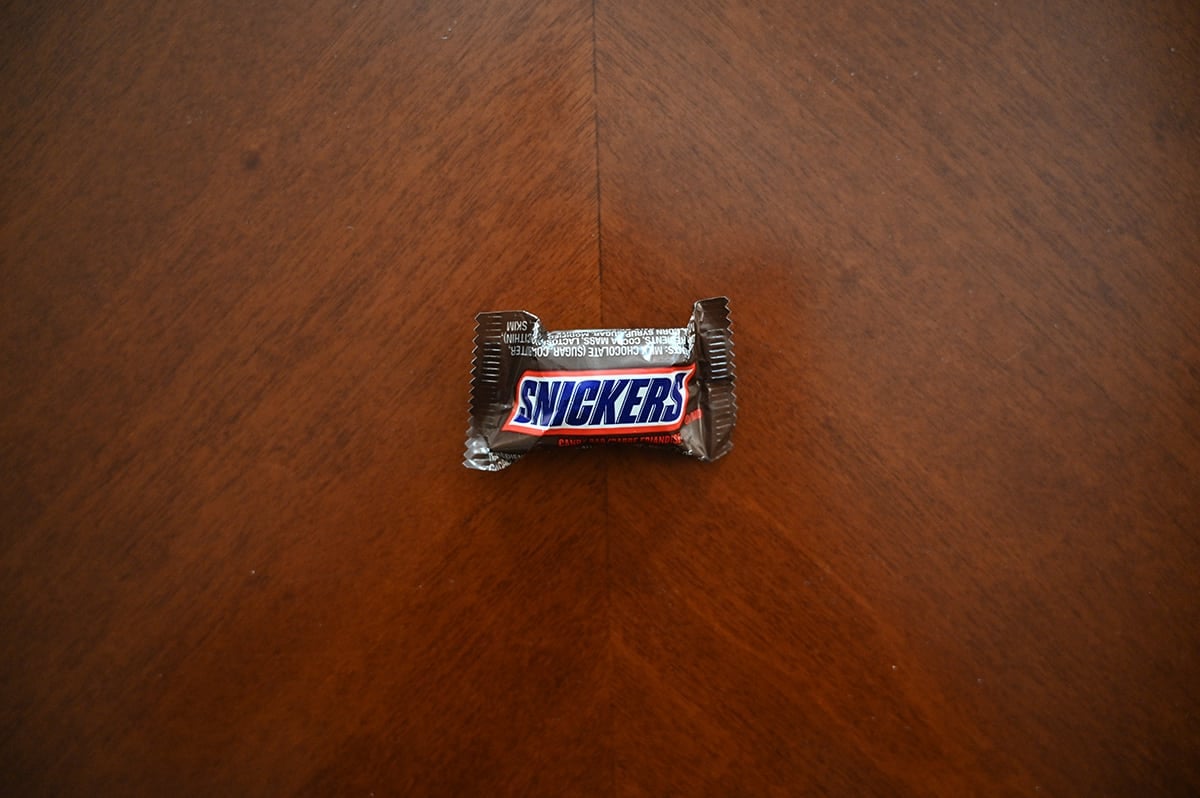 Top down image of a Snickers bar unopened sitting on a table.