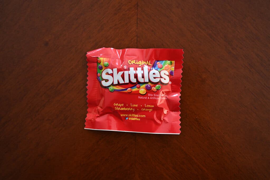 Top down image of an unopened bag of Skittles sitting on a table.