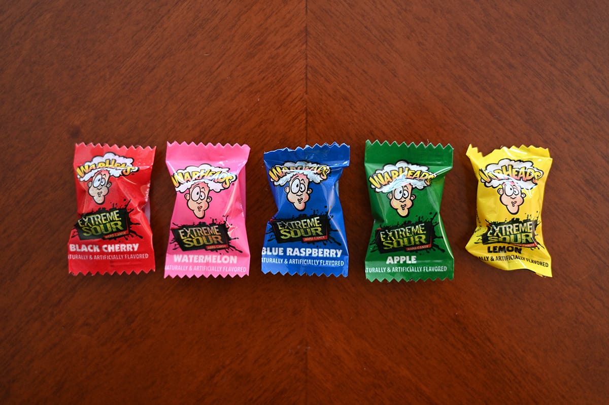 Top down image of five Warhead candies in their packages sitting on a table. There are five different flavors.