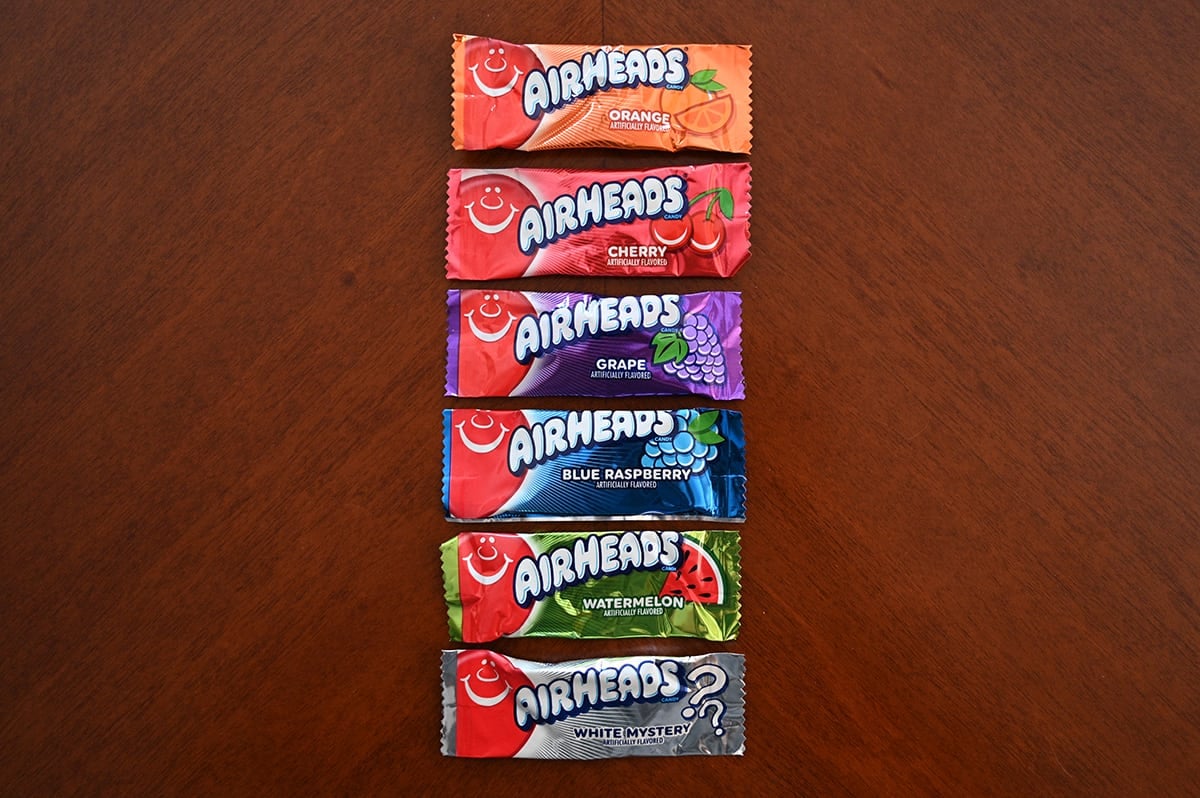 Top down image of six Airheads unopened sitting on a table. There are six different flavors.
