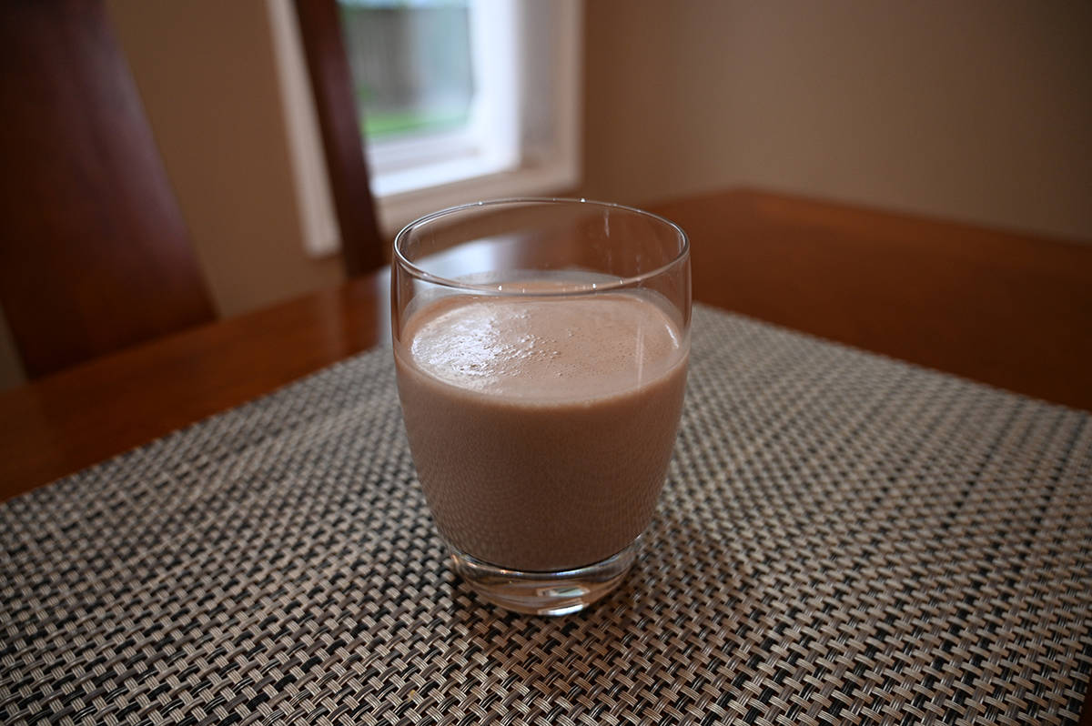 Sideview image of a clear glass with chocolate protein shake in it.