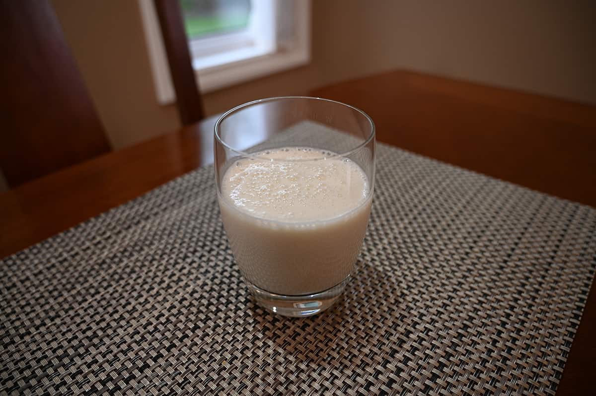 Sideview image of a clear glass with vanilla protein shake in it.