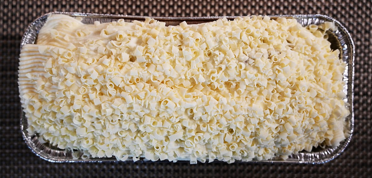 Top down image of the pumpkin spice loaf out of the packaging so you can see the top of the loaf covered in icing and white chocolate curls.