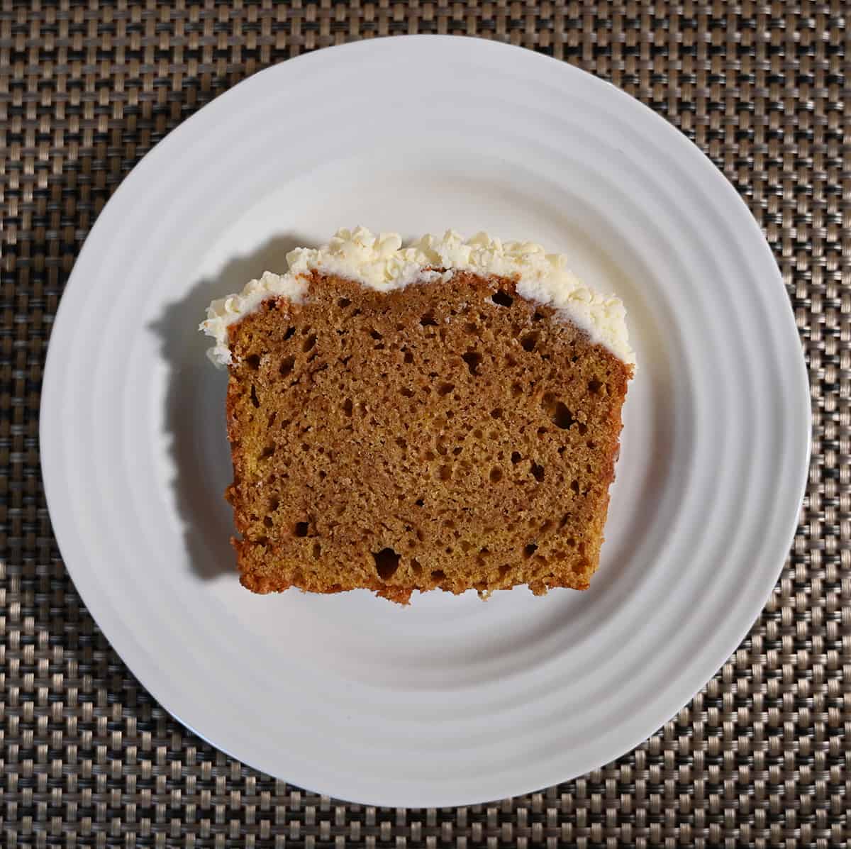 Top down image of one slice of pumpkin spice loaf served on a white plate. The slice is laying on its side so you can see how fluffy and moist it looks.