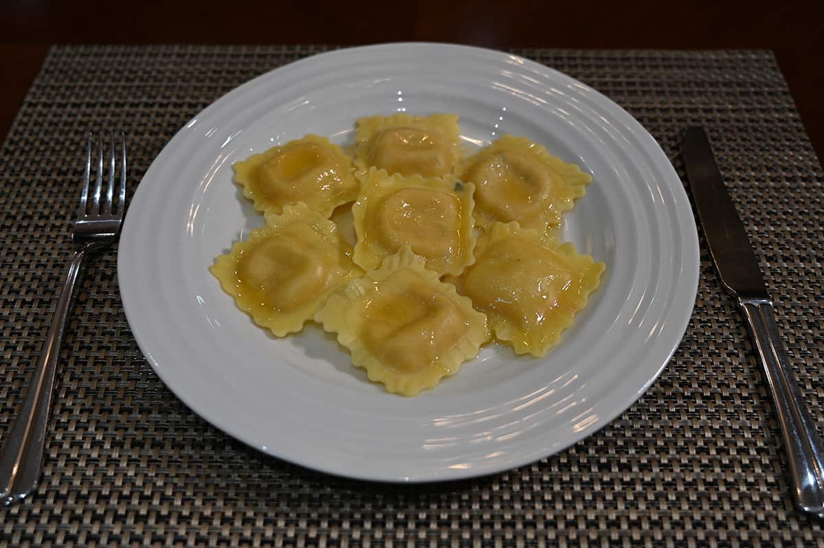 Top down image of a plate of cooked ravioli with a butter sauce on it.