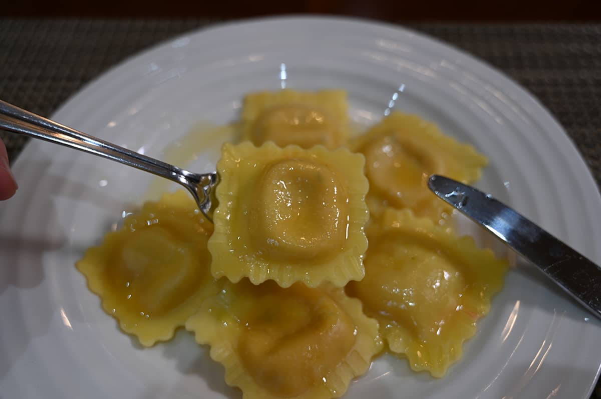 Closeup image of a fork with one whole ravioli on it close to the camera. 