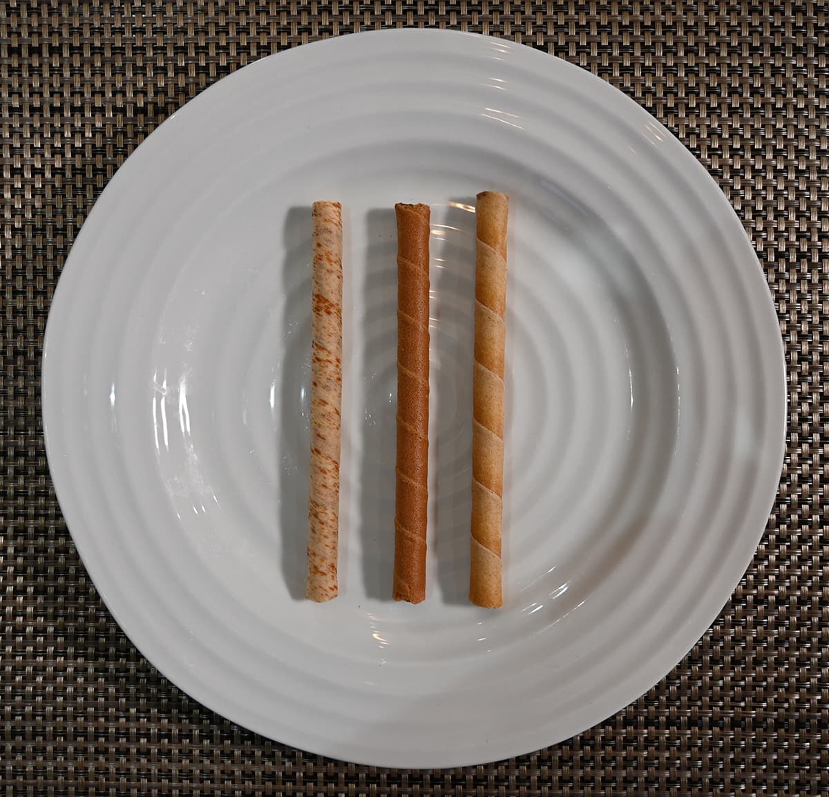 Top down image of three rolled wafers on a plate, vanilla, chocolate and hazelnut.