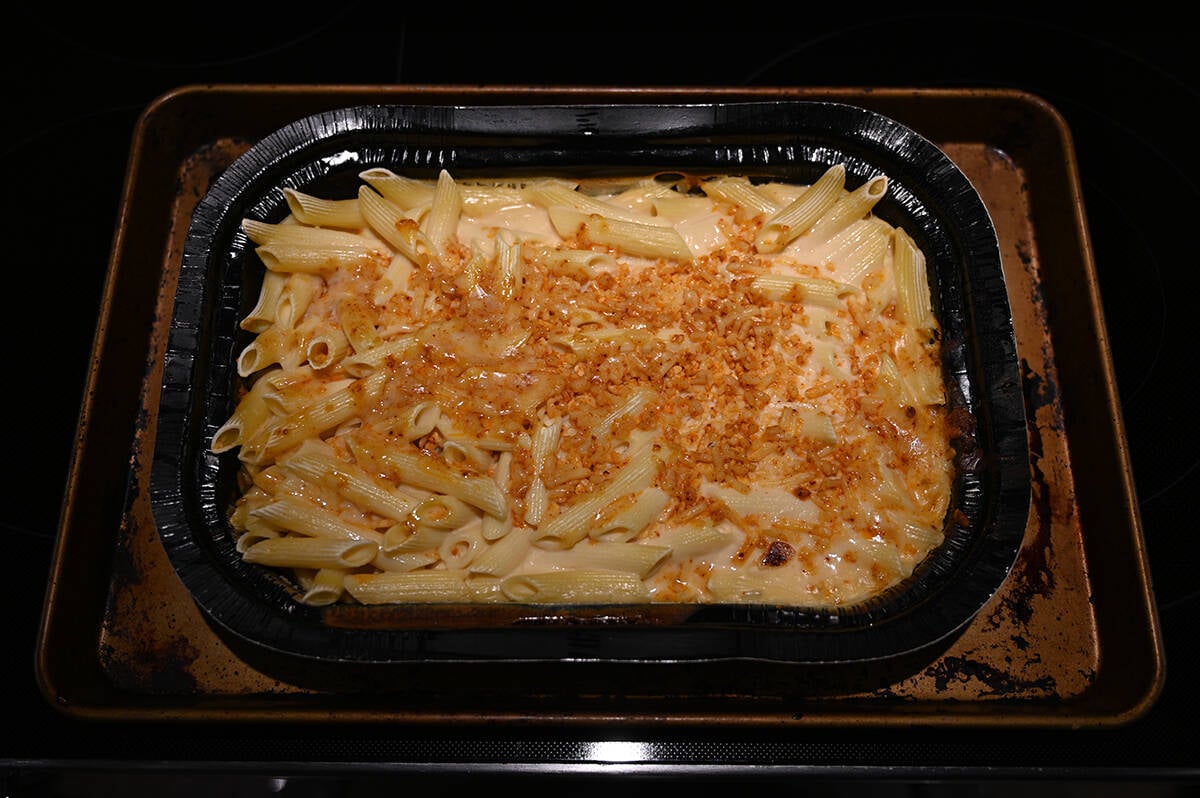 Top down image of the tray of mac and cheese out of the oven after removing the plastic film but before baking it uncovered.