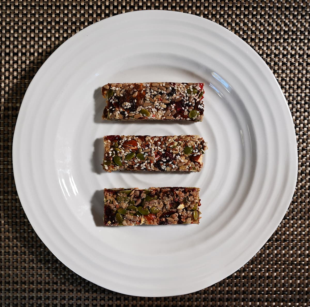 Top down image of three Vel bars on a white plate unwrapped. From top to bottom fruit & nut, flax cranberry and almond berry.