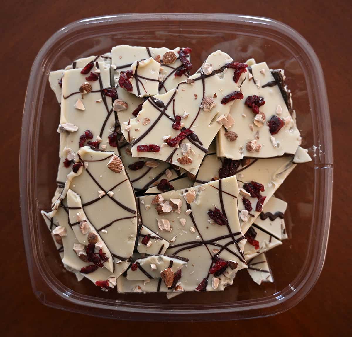 Top down image of an opened container of cranberry almond bark sitting on a table so you can see the almond bark.