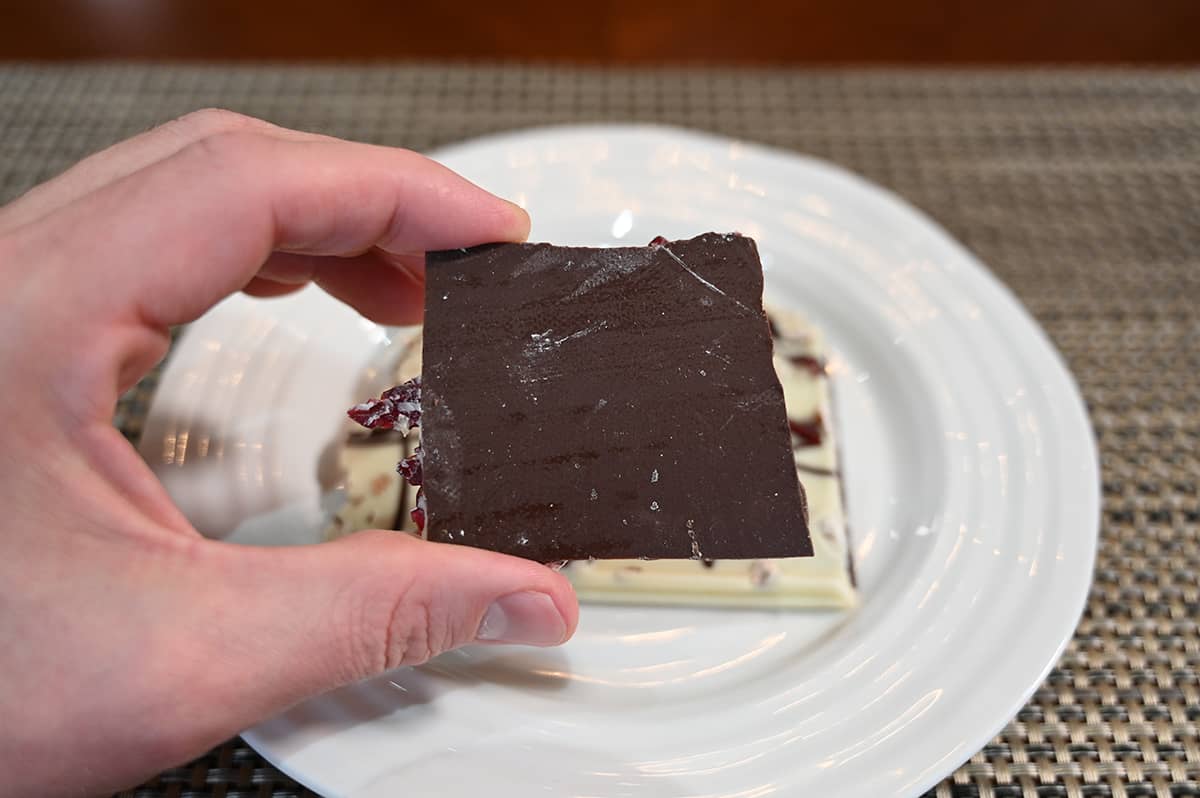 Closeup image of the bottom of a piece of cranberry almond bark showing the dark chocolate on the bottom. 