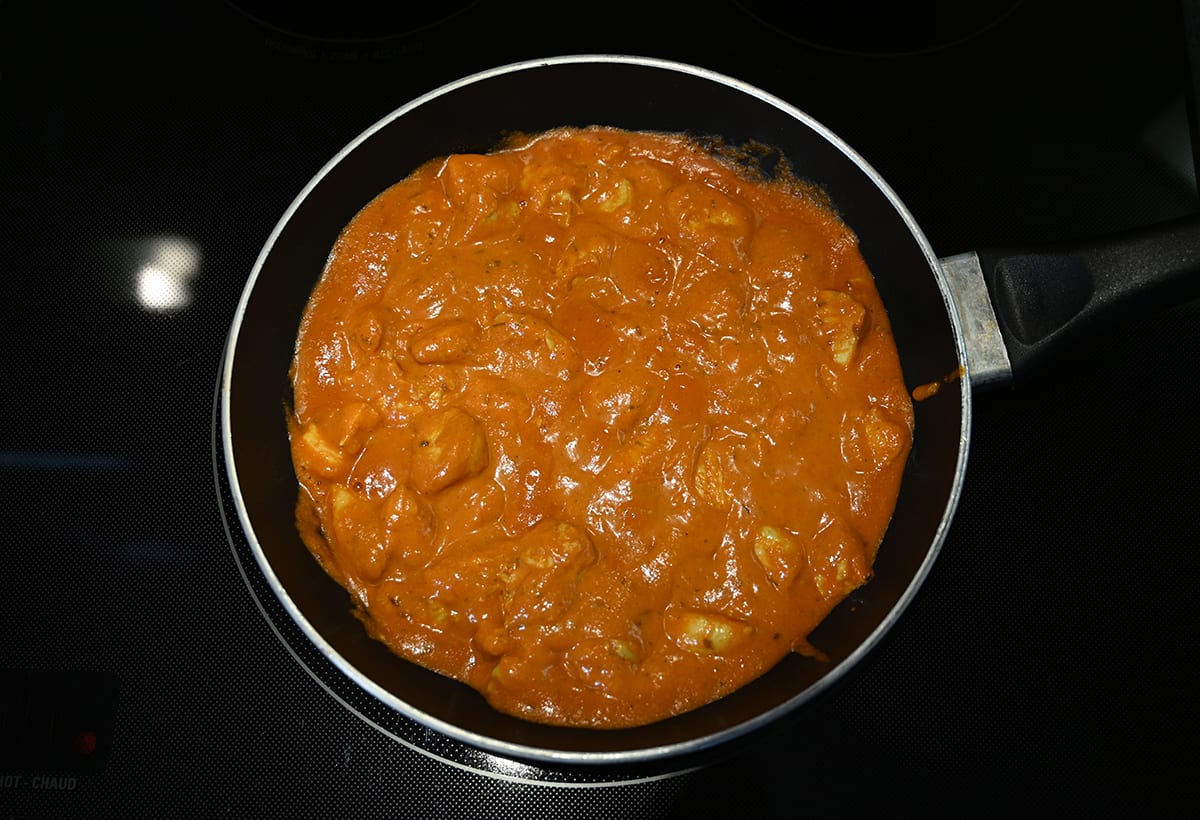 Top down image of the chicken tikka masala being heated in a pan.
