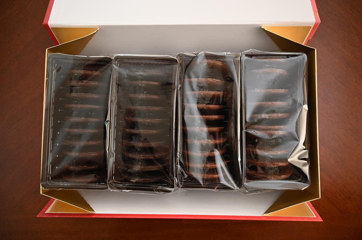 Top down image of four sleeves of cookies packaged in plastic sitting in a box.