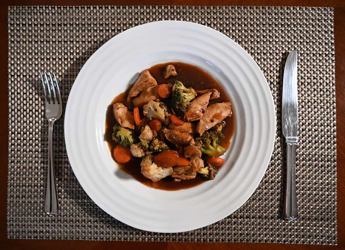 Image of the teriyaki chicken stir-fry served on a white plate sitting on a table with a fork and knife beside it.