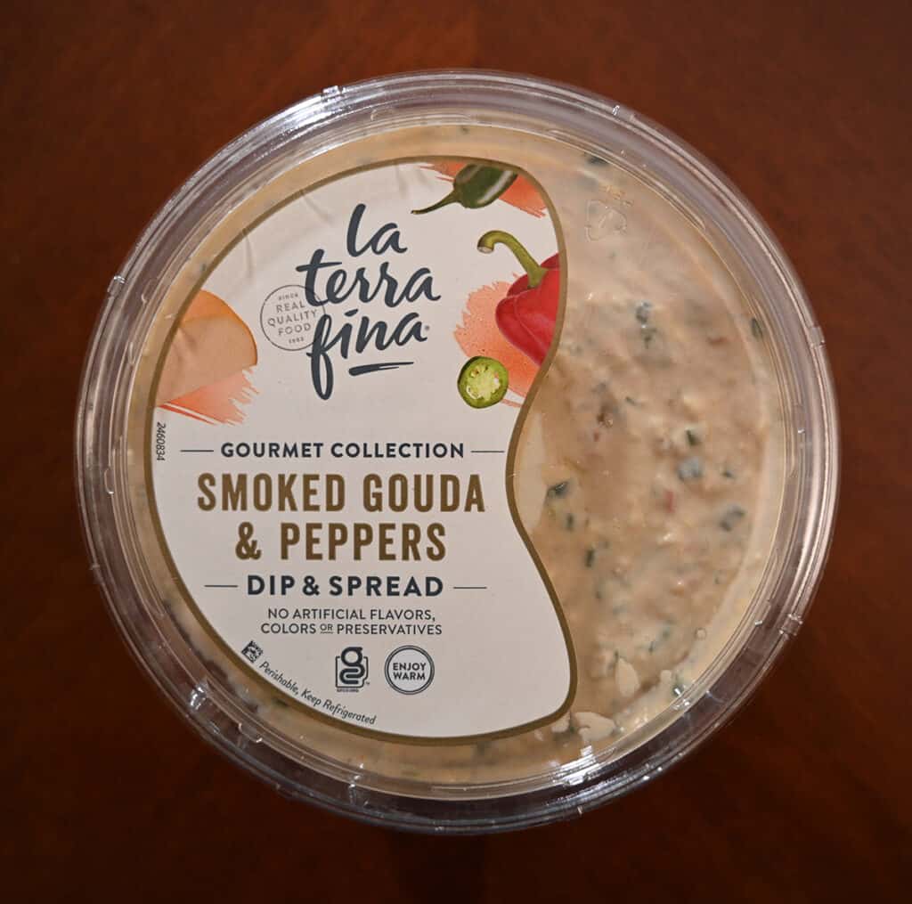 Top down image of the top label on an unopened smoked gouda & peppers dip. Showing to serve warm and there are no artificial flavors.