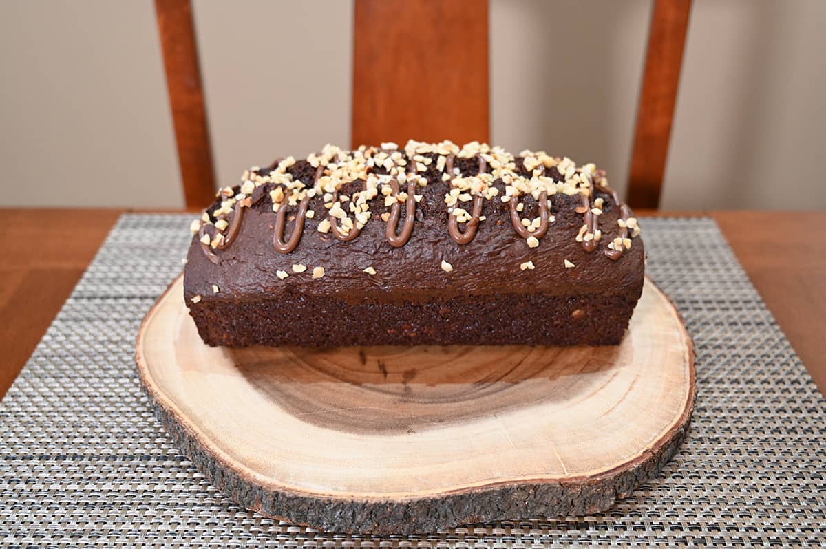 Side view image of the hazelnut loaf out of the package and served on a cutting board, not yet sliced.