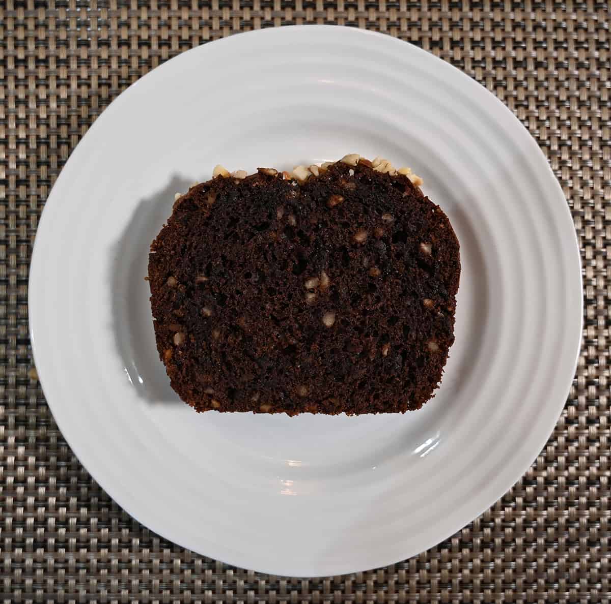 Top down image of one slice of hazelnut loaf on a white plate.