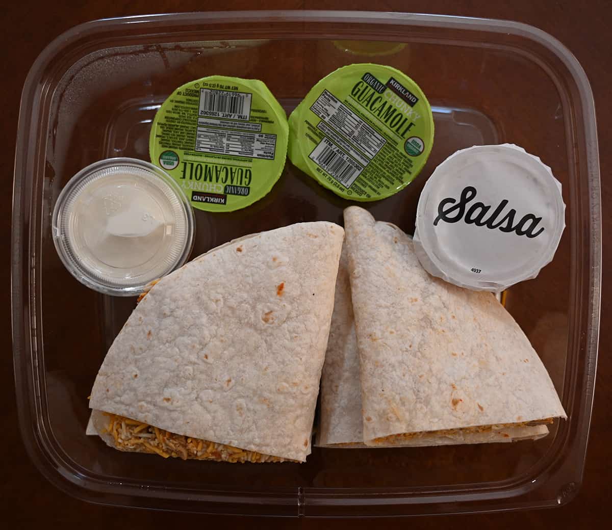 Top down image of the quesadillas containers opened so the quesadillas and sauces are visble. 