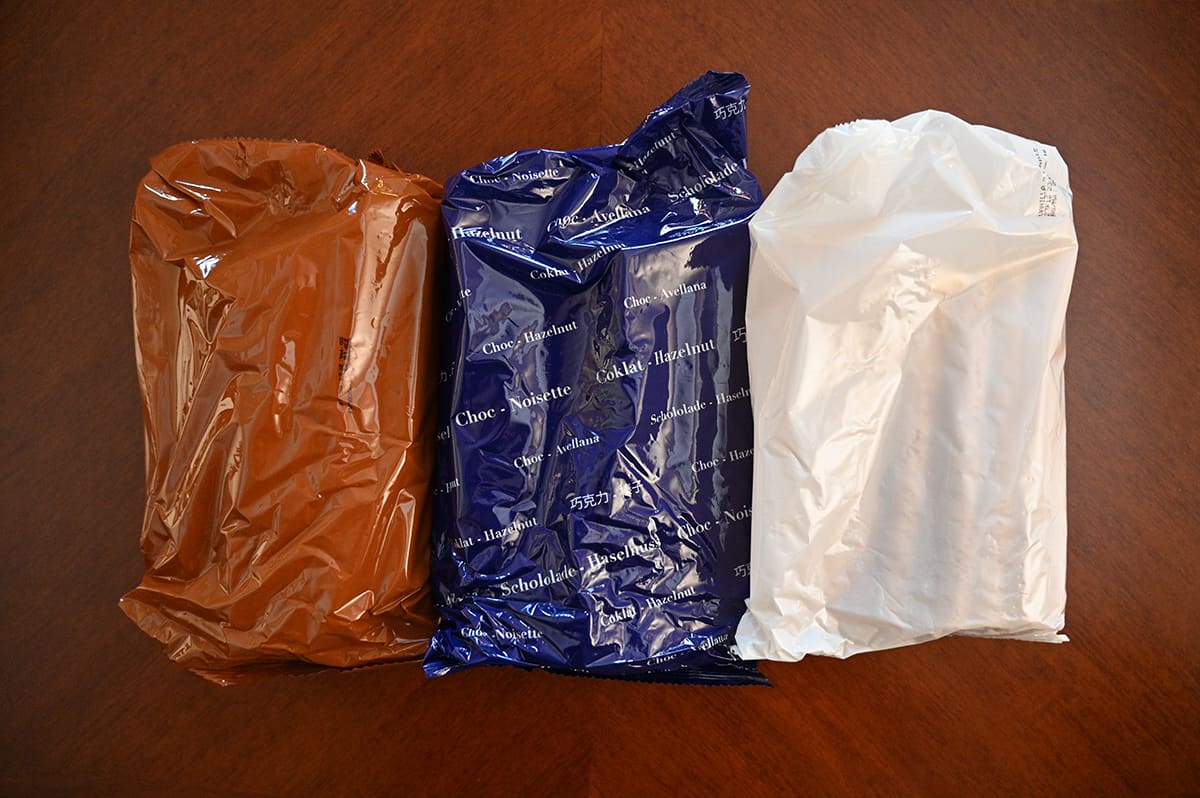 Top down image of three bags of rolled wafers removed from the tin and sitting on a table, there is a brown, blue and white bag.