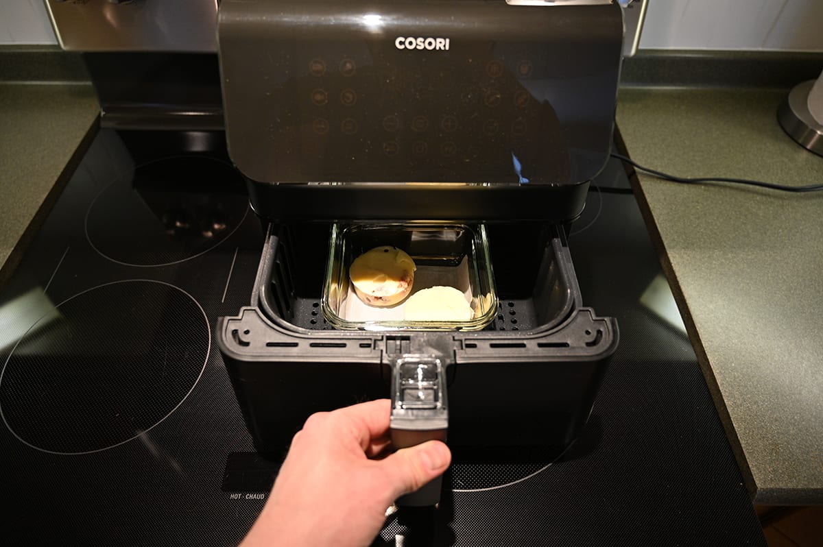 Image of a someone pulling two egg bites out of the air fryer after being cooked in it.