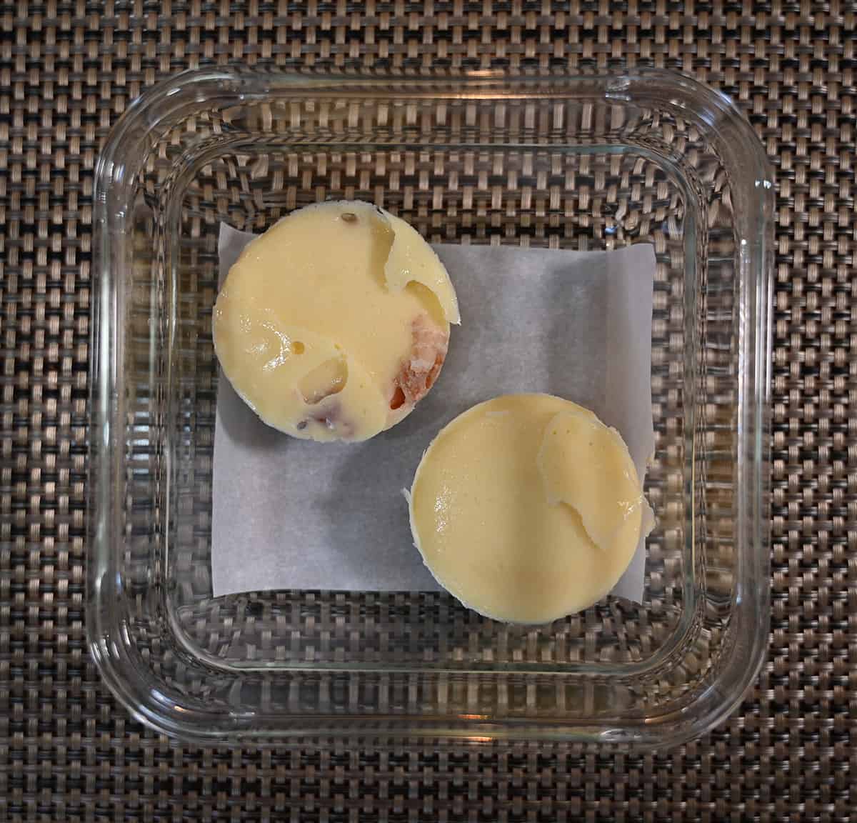 Top down image of two uncooked egg bites sitting in the tray they come in prior to cooking them.