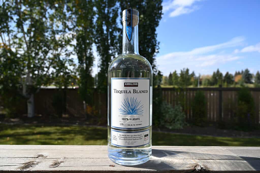 Image of the Kirkland Signature Tequila Blanco bottle sitting on a deck outside unopened.