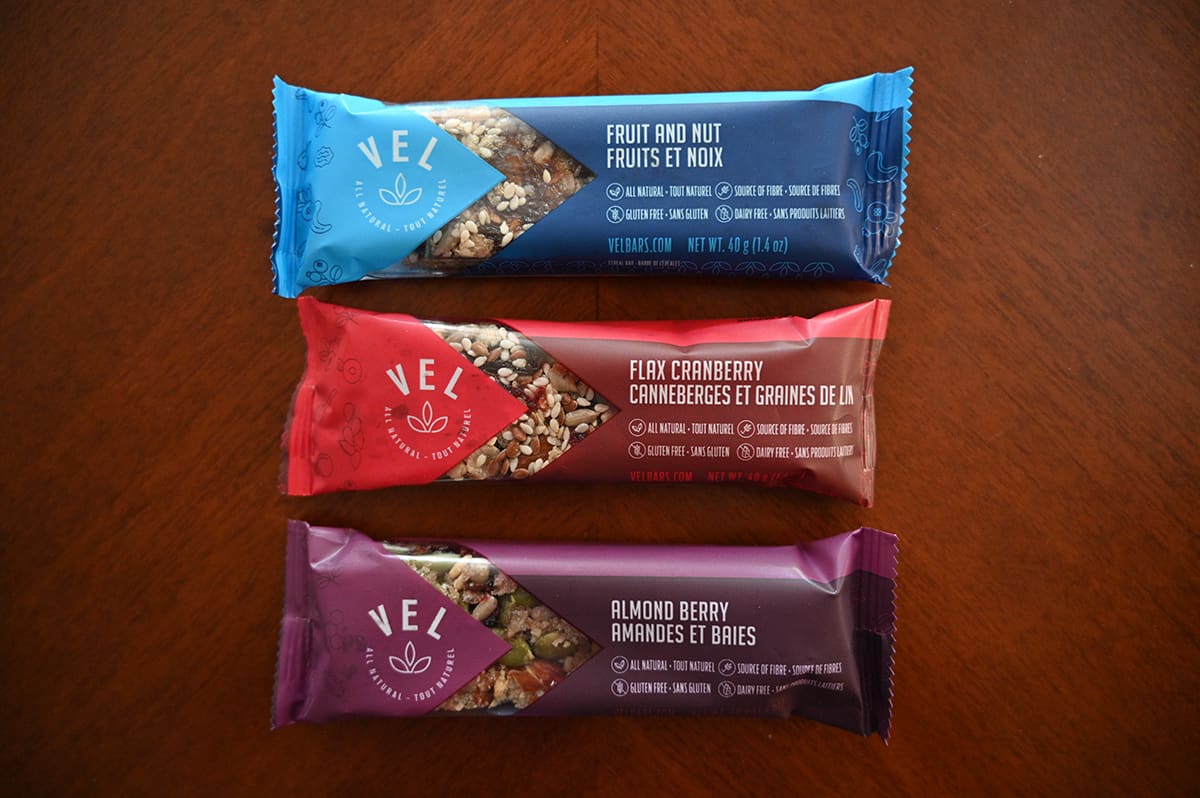 Top down image of three Vel bars on a table in their package. Fruit & nut, flax cranberry and almond berry.